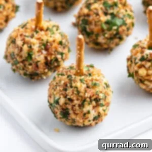 close up mini cheese balls coated in crushed nuts with a pretzel stick