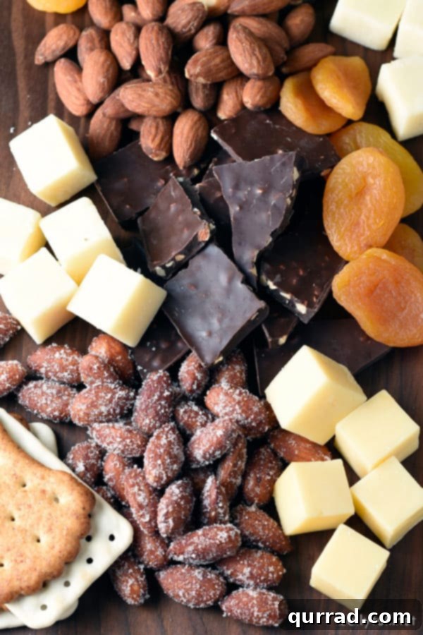 Build a simple, stunning cheese and nut board in just 15 minutes! An overhead shot showcasing a beautiful assortment of cheeses, various nuts, decadent dark chocolate pieces, and vibrant dried fruits on a wooden serving board.