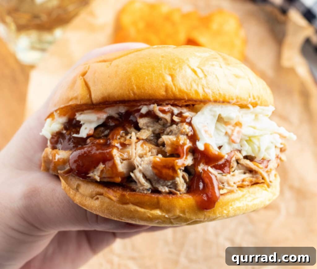 The Ultimate Pulled Pork 4 Close up shot of a delicious shredded pulled pork sandwich with BBQ sauce and creamy coleslaw.