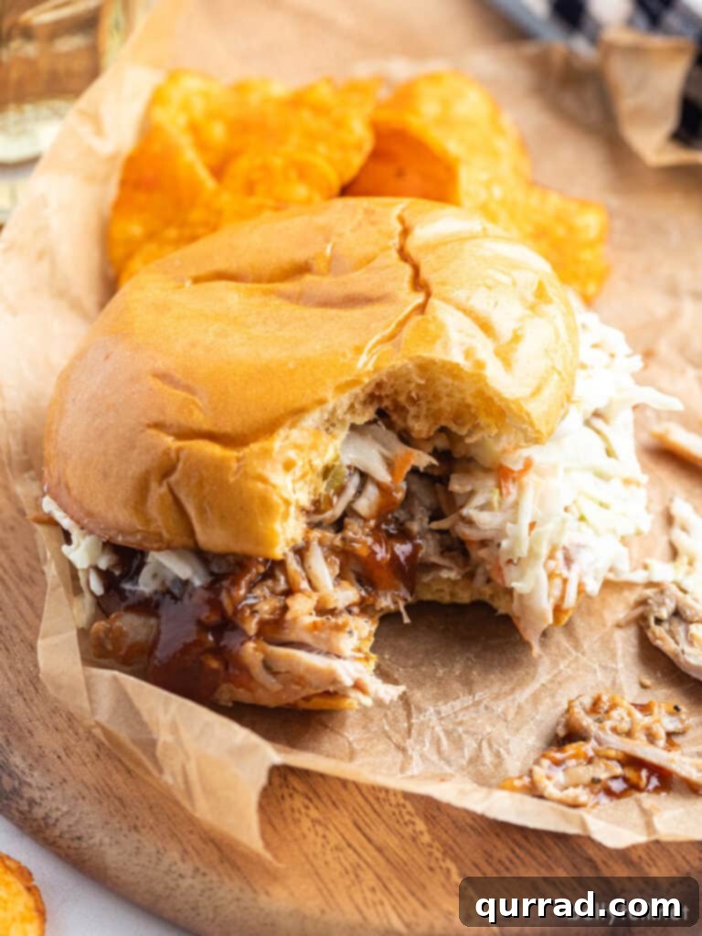 The Ultimate Pulled Pork 5 Close up of a shredded pork sandwich with a bite taken out, highlighting its tenderness.