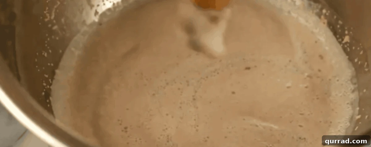 Cheesy Ghoul Rolls 4 Yeast foaming in a stainless steel bowl after being combined with warm water and sugar, showing proper activation.