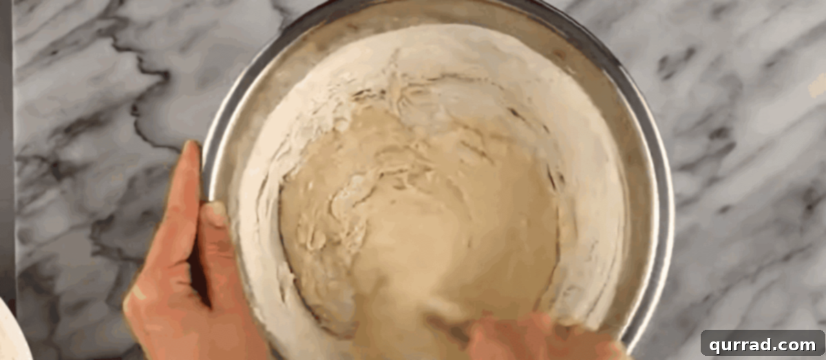 Cheesy Ghoul Rolls 5 Adding milk, softened butter, salt, sugar, egg, and flour to the foamed yeast mixture in a mixing bowl.