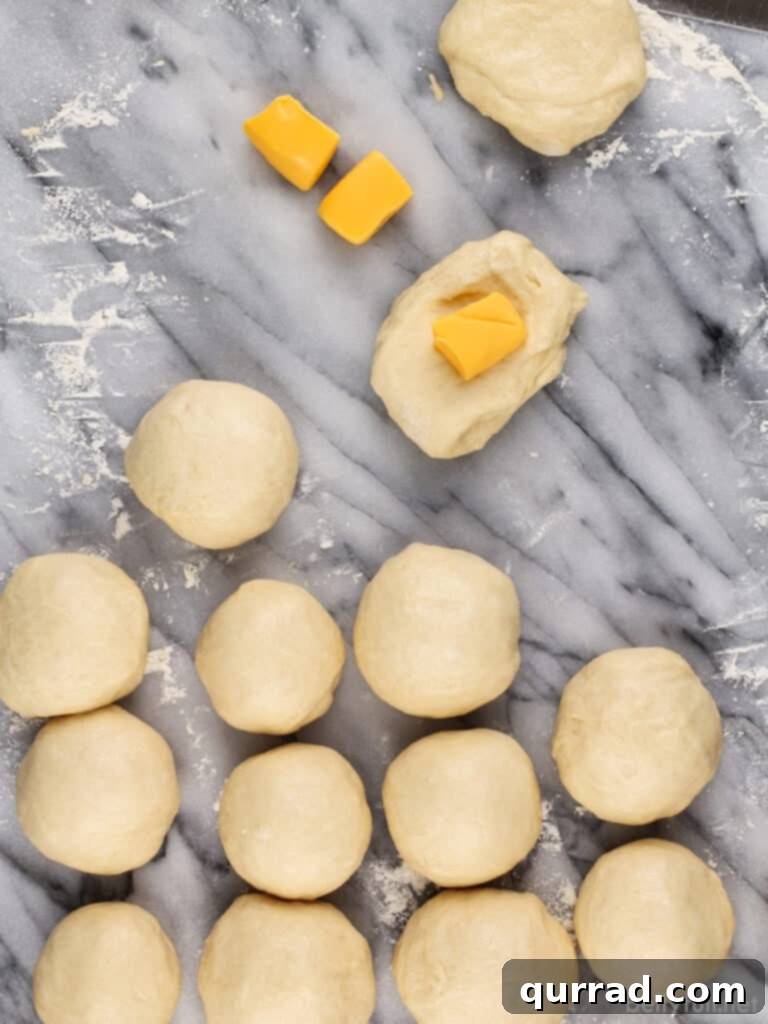 Cheesy Ghoul Rolls 7 Raw dough rolls being stuffed with cubes of Velveeta cheese, with hands pinching the dough shut.