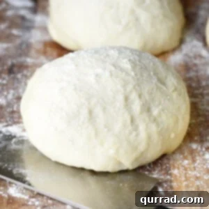 A perfectly formed round of homemade pizza dough on a clean cutting board.