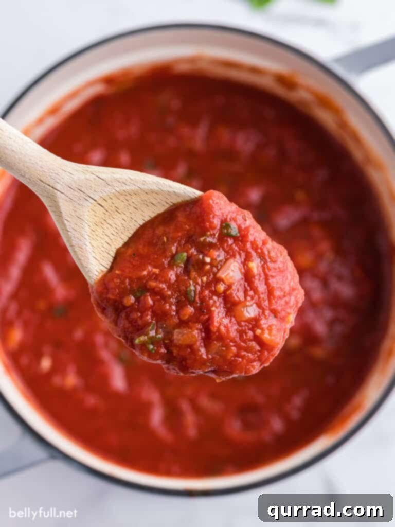 Slow-Simmered Marinara Sauce 2 overhead close up marinara sauce on wooden spoon, showcasing its rich texture and vibrant color