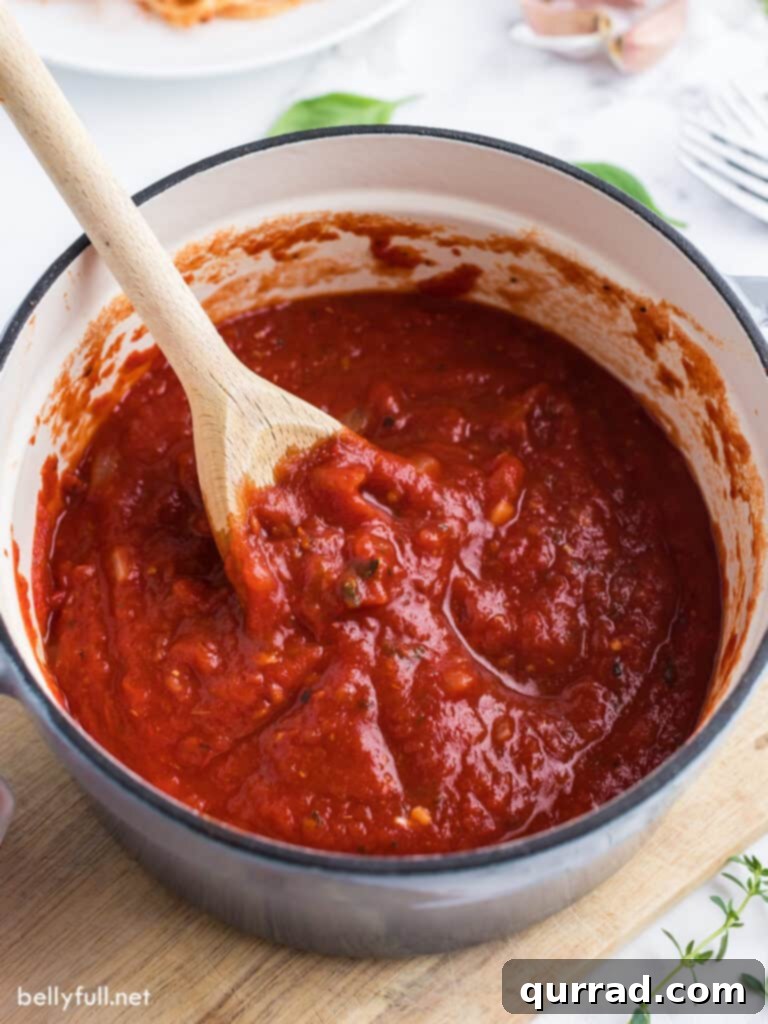 Slow-Simmered Marinara Sauce 3 marinara sauce simmering gently in a saucepan, with a wooden spoon resting inside