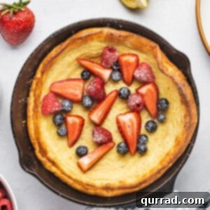 Close-up of a Dutch Baby pancake in a cast iron skillet with fresh berries.