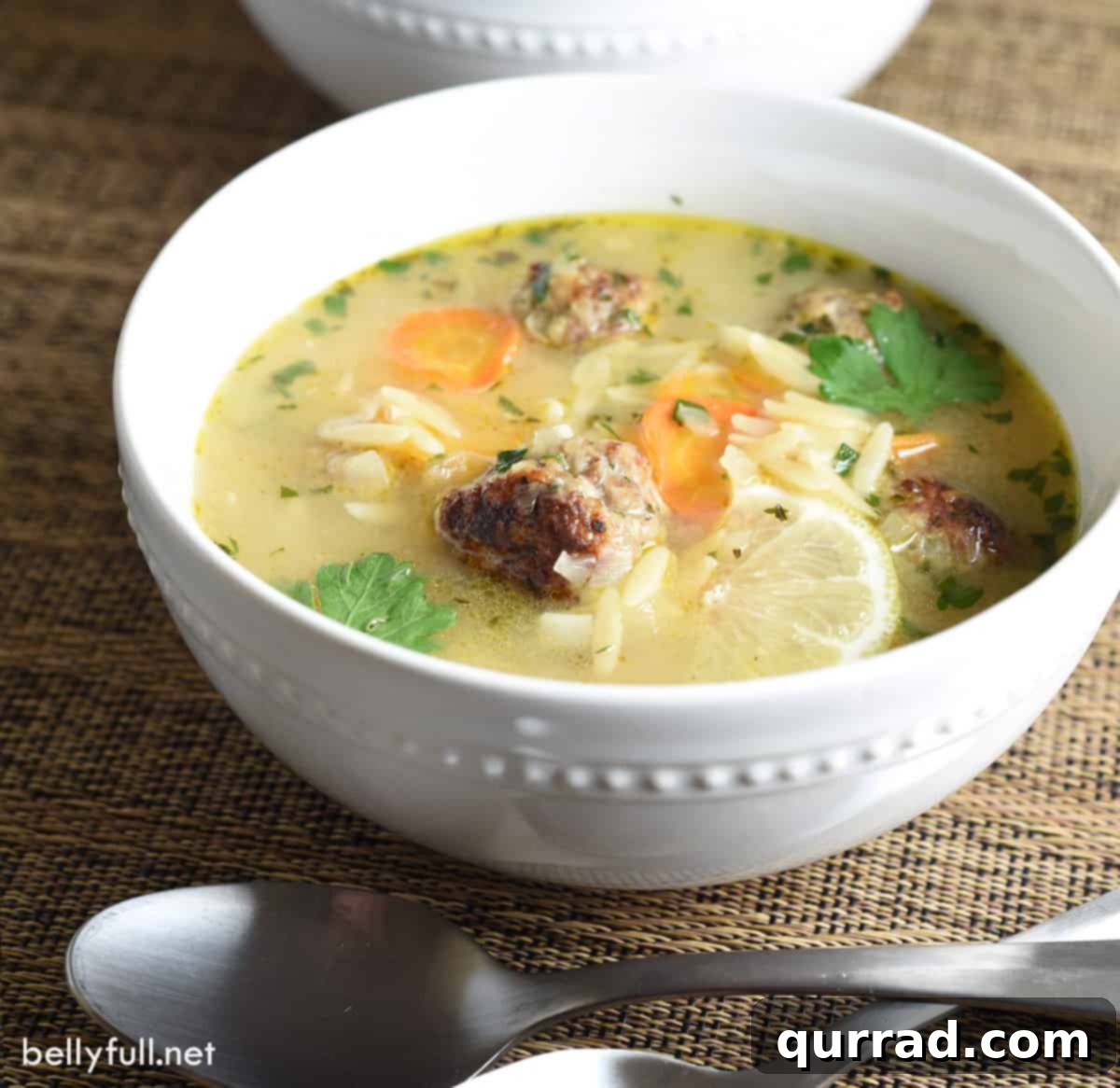 Hearty Meatball Soup 4 meatball soup with orzo and lemon slice in white bowl
