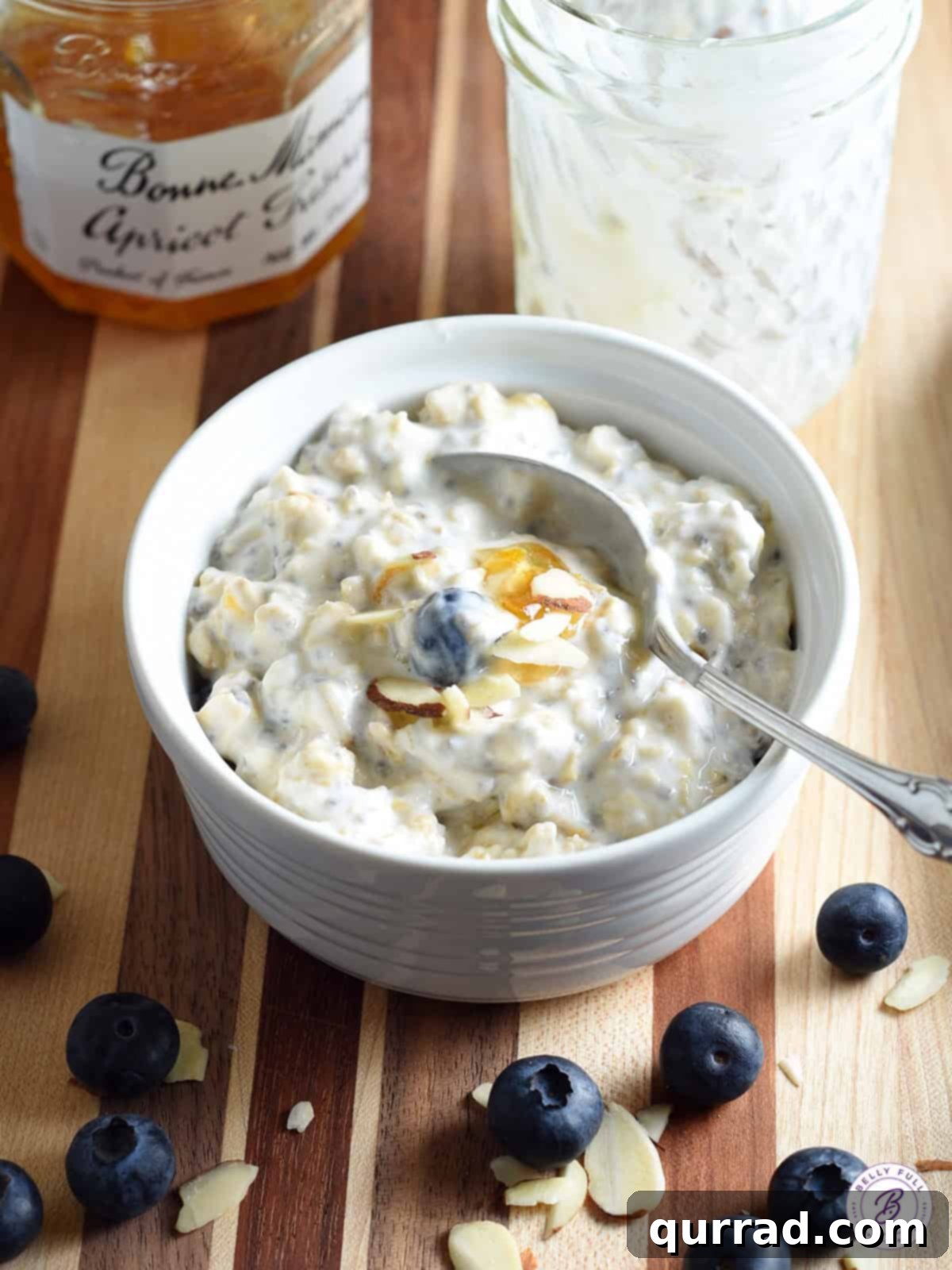A bowl of creamy overnight oatmeal garnished with fresh blueberries and a sprinkle of sliced almonds, showcasing its appealing texture.