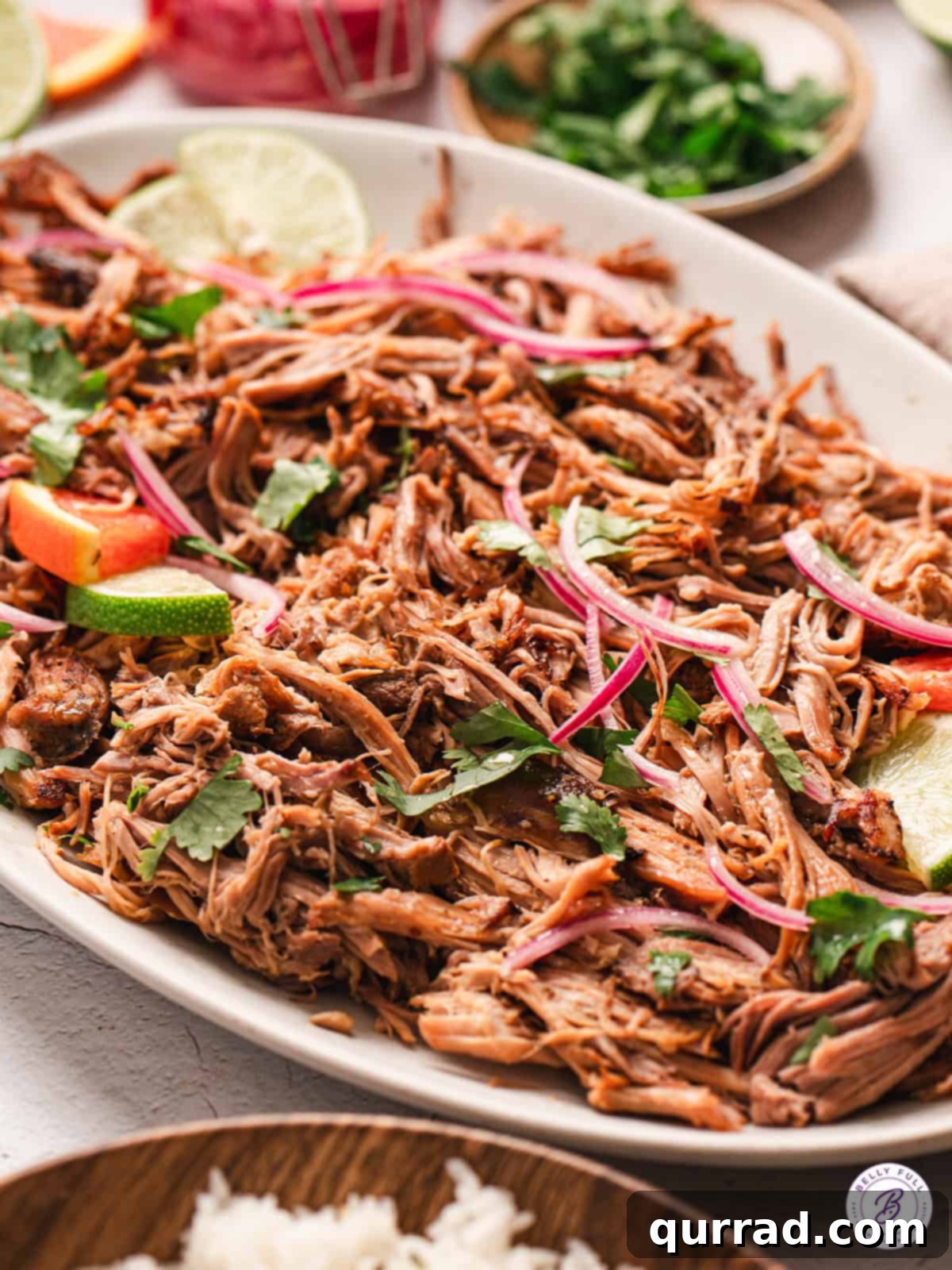Shredded Cuban pork with lime wedges on a serving plate, ready to be enjoyed.