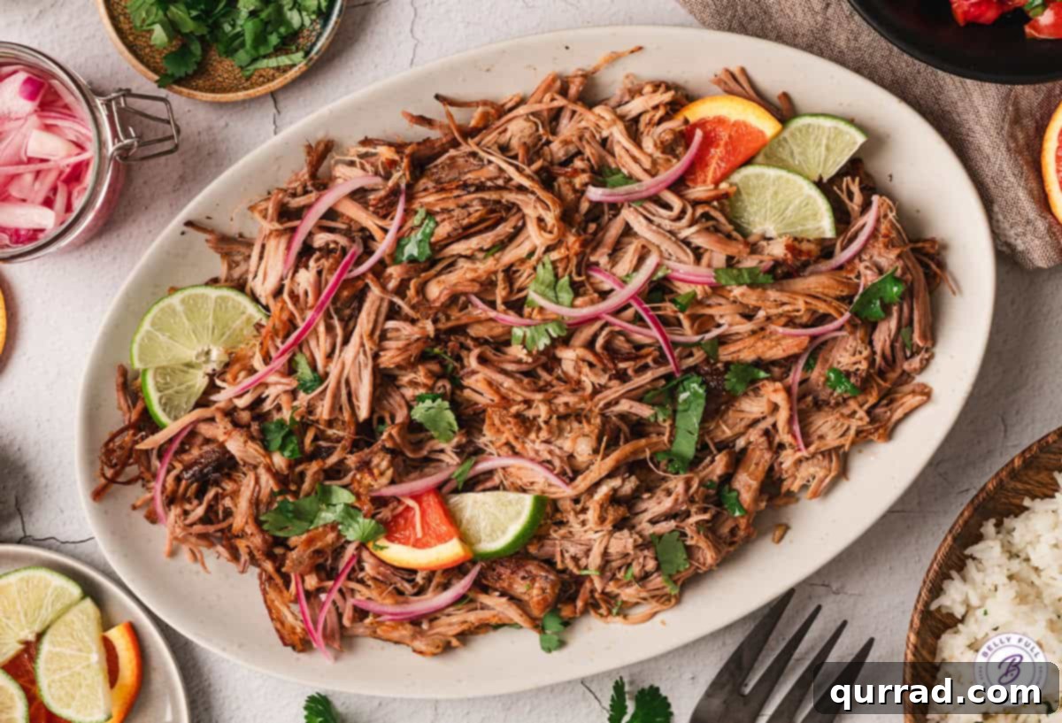Shredded Cuban pork with lime wedges on a serving plate, close-up view.