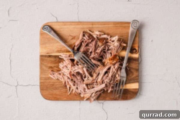 Shredded pork carnitas on a cutting board, ready for the next step.