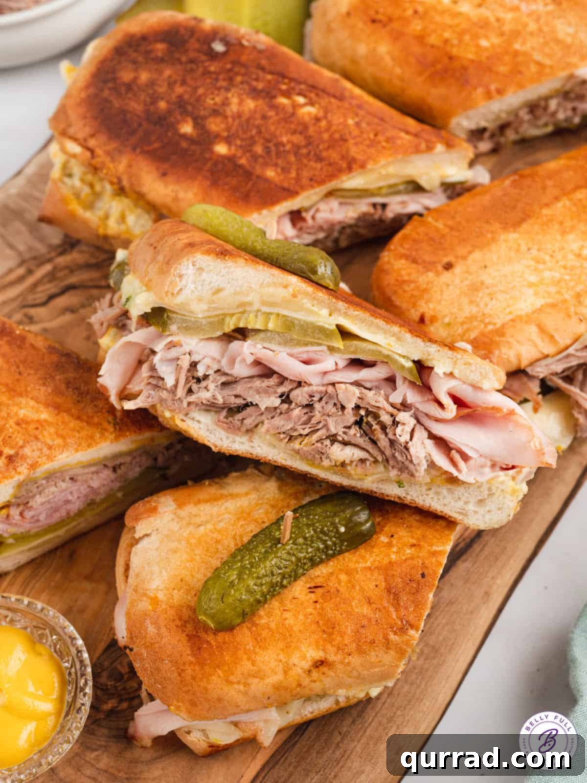 Havana's Golden Press 3 Multiple Cuban sandwiches cut in half, arranged on a wooden cutting board, showcasing their rich fillings.