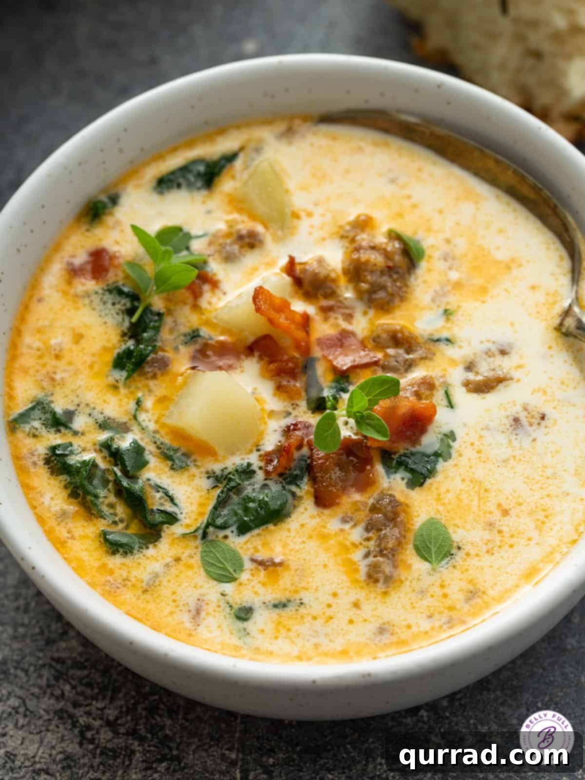 Hearty Zuppa Toscana Soup: Olive Garden Copycat A bowl of Zuppa Toscana soup generously loaded with potatoes, crumbled sausage, and crispy bacon bits, ready to be enjoyed.
