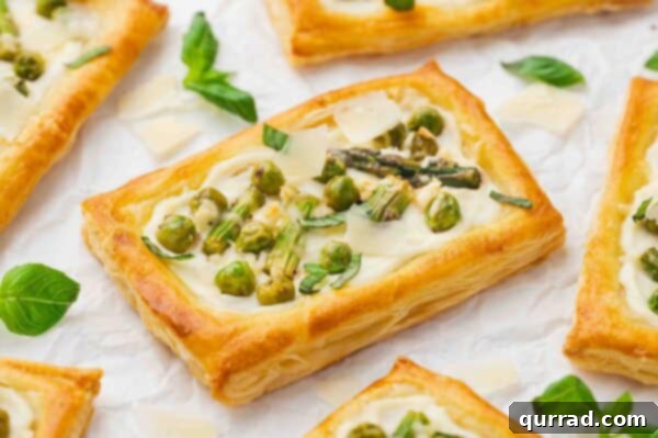 Springtime Asparagus Gems 11 Close-up of freshly baked Asparagus Puff Pastry Tarts on parchment paper, garnished and ready to serve.