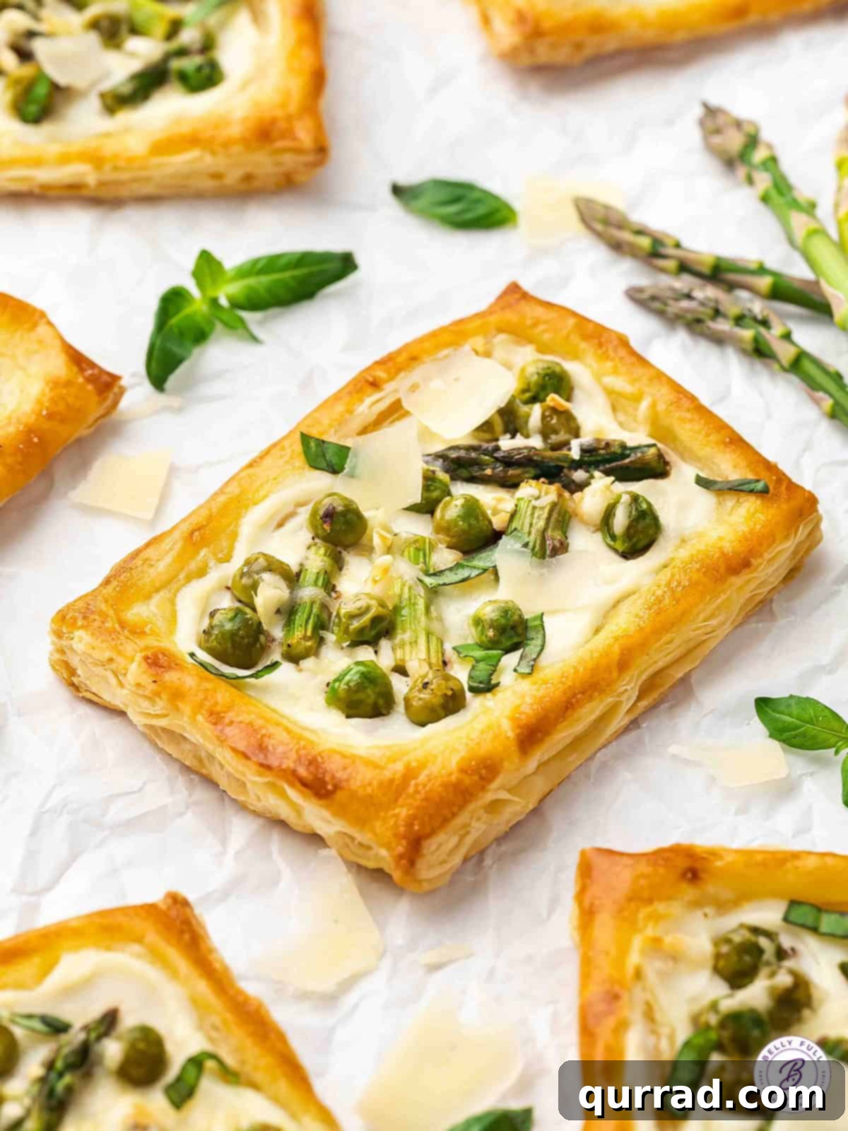 Springtime Asparagus Gems 13 Close-up of baked Asparagus Puff Pastry Tarts on parchment paper, ready to be served and enjoyed.
