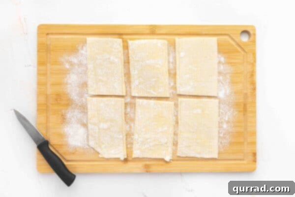 Springtime Asparagus Gems 4 Overhead view of 6 unbaked puff pastry rectangles on a cutting board, ready for scoring.