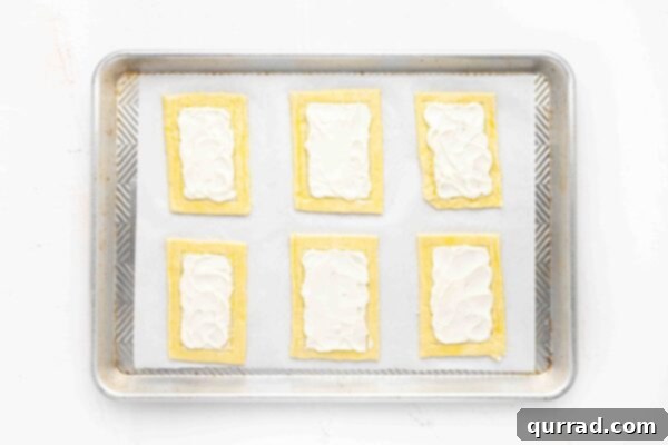 Springtime Asparagus Gems 7 Overhead view of 6 unbaked puff pastry rectangles on parchment paper with creamy ricotta spread in the center.