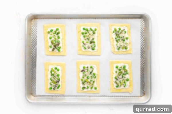 Springtime Asparagus Gems 9 Overhead view of 6 unbaked Asparagus Puff Pastry Tarts, fully assembled with ricotta, vegetables, garlic, and Parmesan.