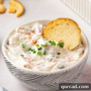 smoked salmon dip in bowl with chives and a cracker