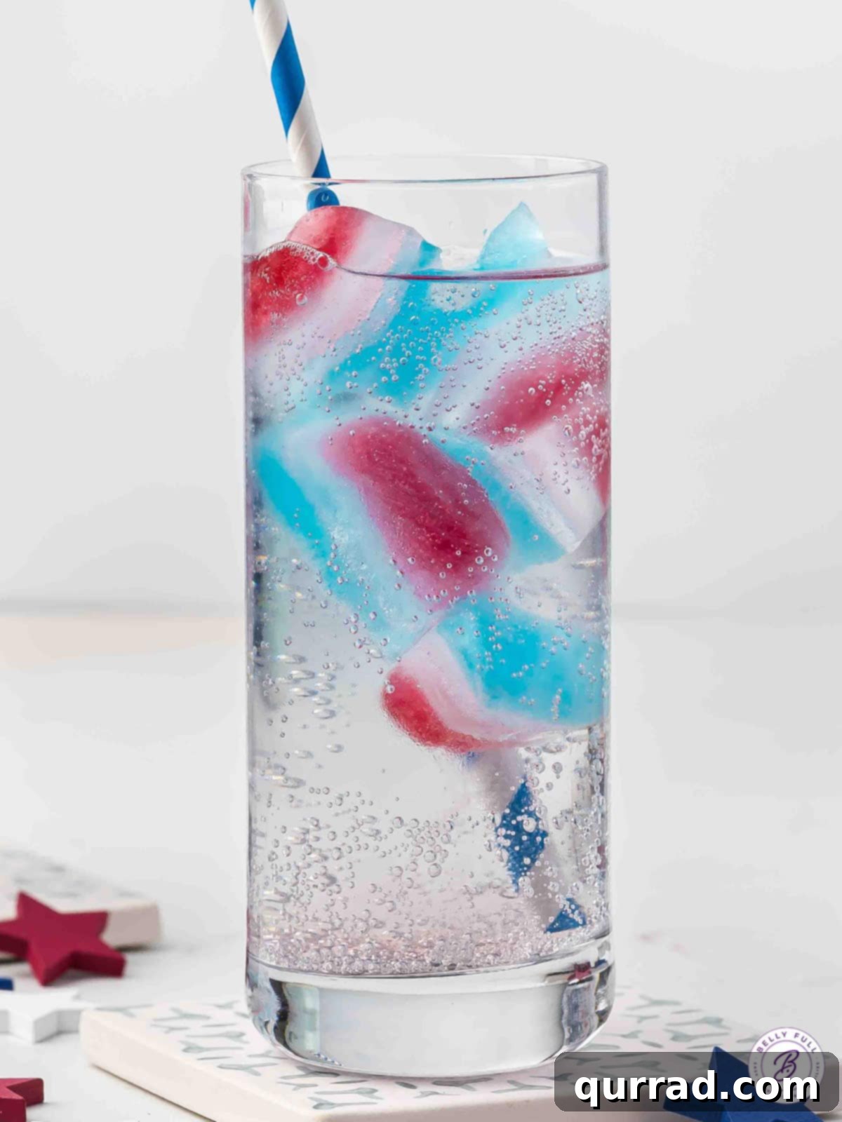 Stars and Stripes Chillers 9 A glass with a straw and red, white, and blue layered ice cubes, ready for a festive drink.
