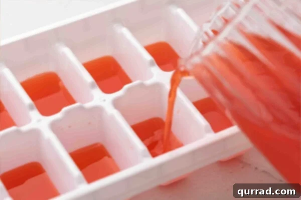Red liquid being poured into an ice cube tray to form the first layer of patriotic ice cubes.