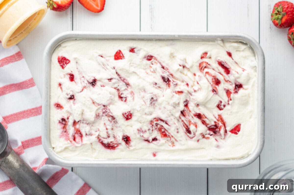 Creamy No-Churn Strawberry Delight 4 A 9x5 inch loaf pan filled with swirling layers of pink strawberry ice cream, showcasing its creamy texture before freezing.