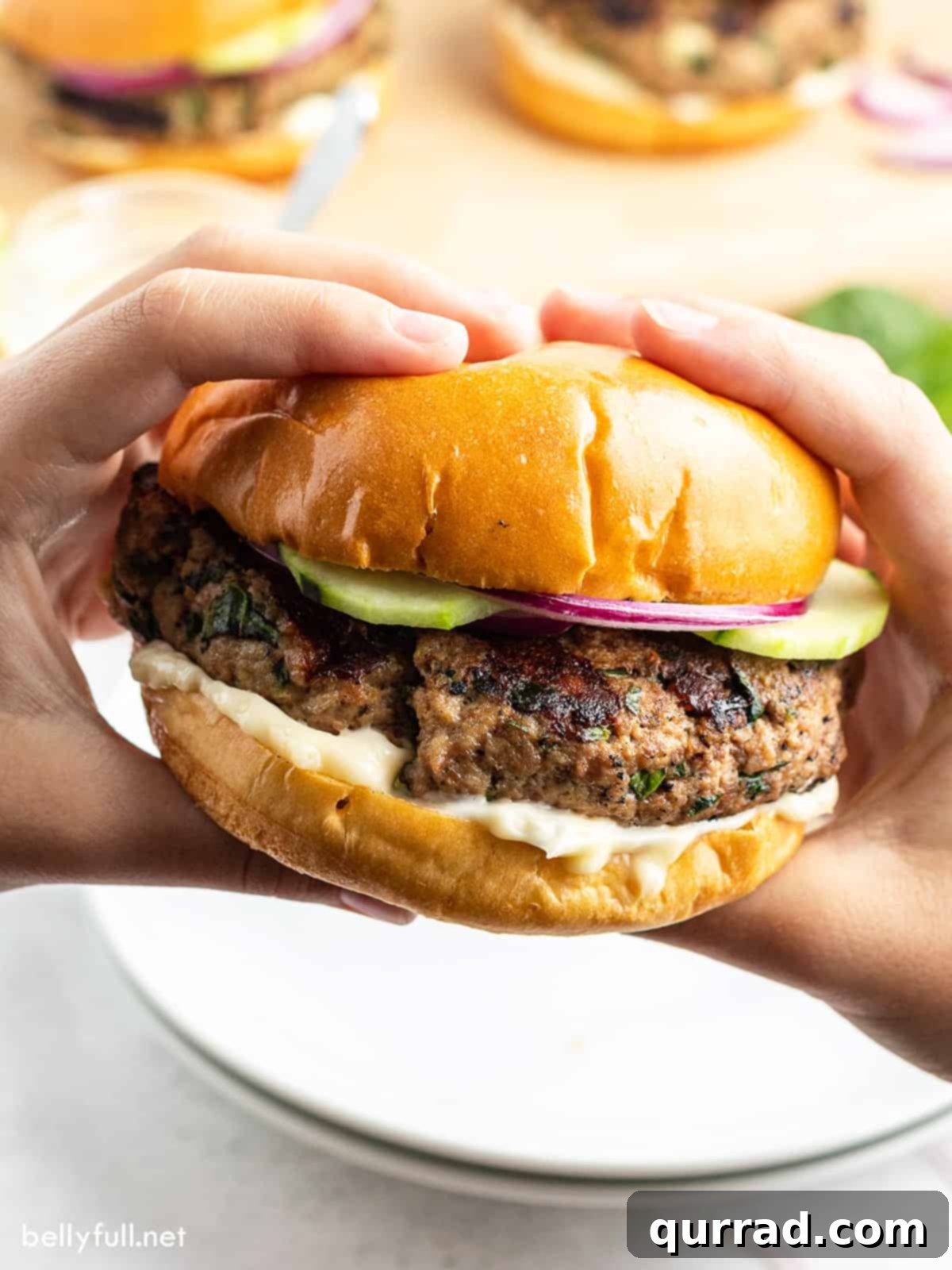 Succulent Turkey Burgers 2 hands holding grilled turkey burger on bun