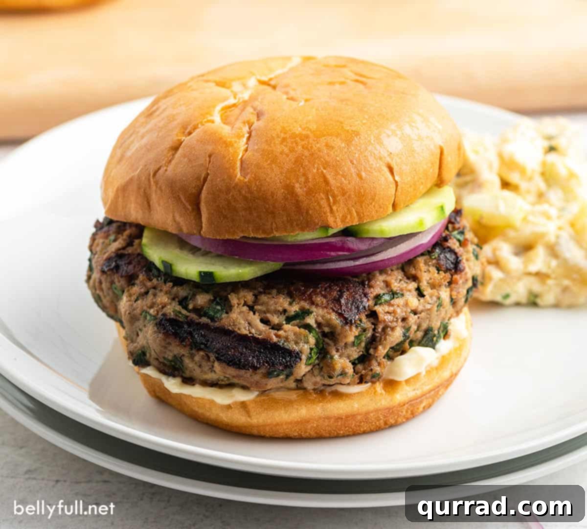 Succulent Turkey Burgers 4 grilled turkey burger with cucumber and onion slices on white plate