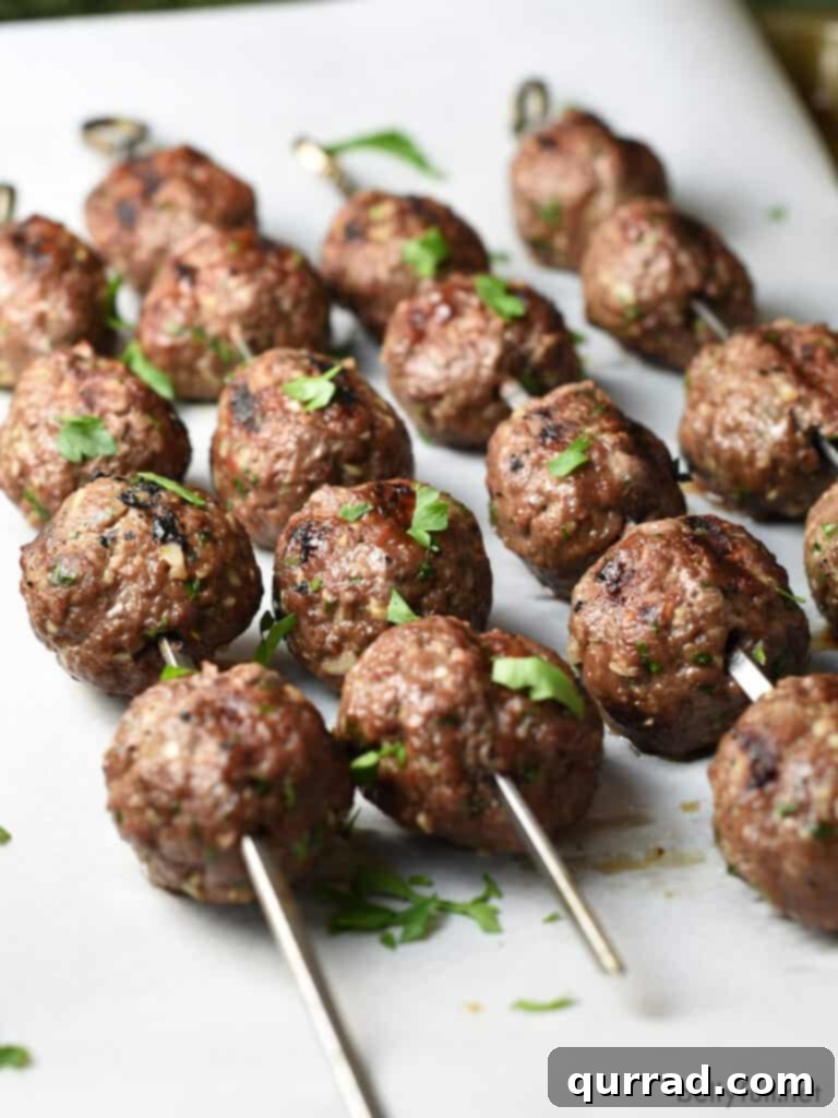 Spiced Beef Kofta Meatballs 3 beef kebob meatballs on metal skewers sprinkled with parsley