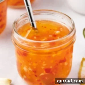 Close-up of a glass jar of homemade sweet chili sauce, highlighting its vibrant red color and thick consistency.