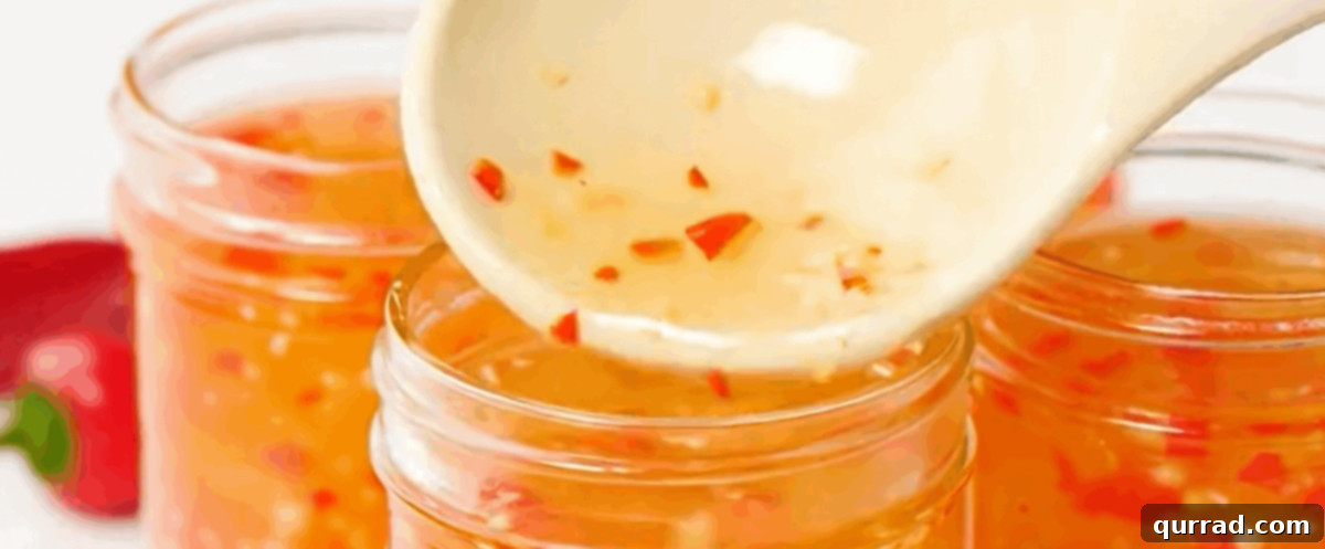 Hot sweet chili sauce being carefully ladled into 8 oz glass canning jars, with a precise measurement of headspace left at the top.