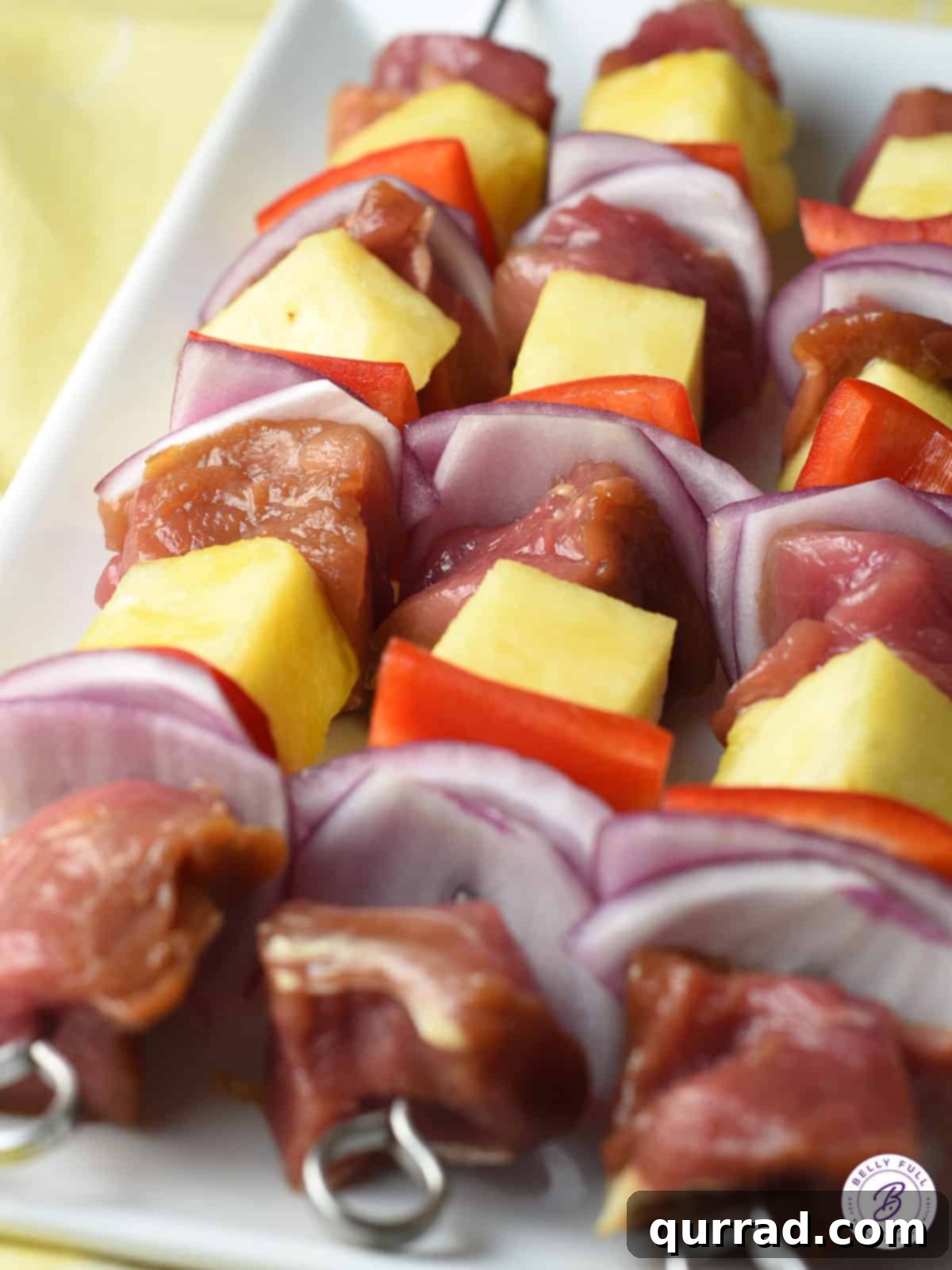 Flame-Kissed Teriyaki Pork Skewers 3 uncooked pork skewers with pineapple and vegetables