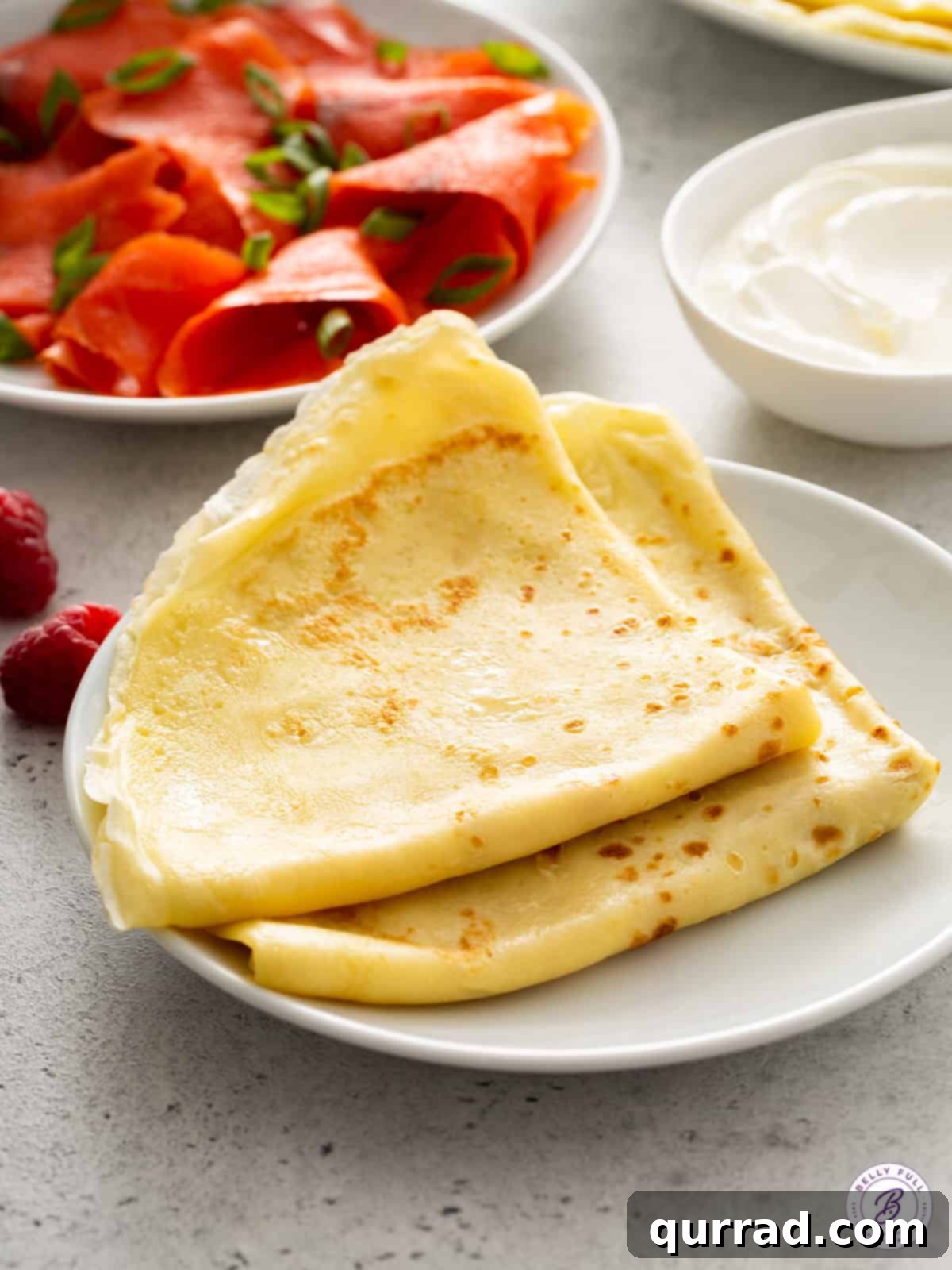 Two stacks of perfectly golden, folded crepes on a clean white plate, ready to be served.