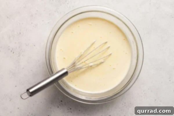 Smooth crepe batter resting in a bowl with a whisk, ready for cooking.