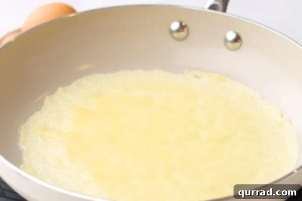 A crepe cooking in a frying pan, its edges just starting to brown and crisp.