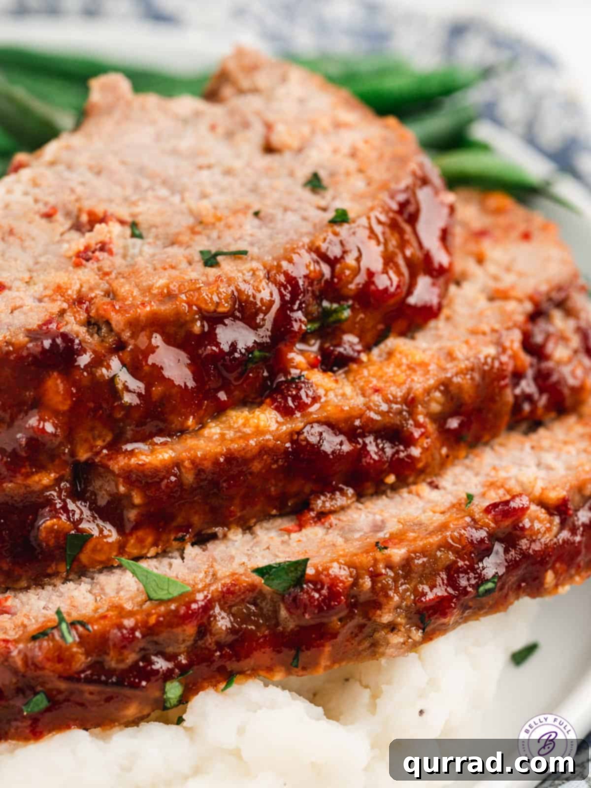 Close-up of three stacked slices of glazed Honey Chipotle Meatloaf, showing the texture and glaze.
