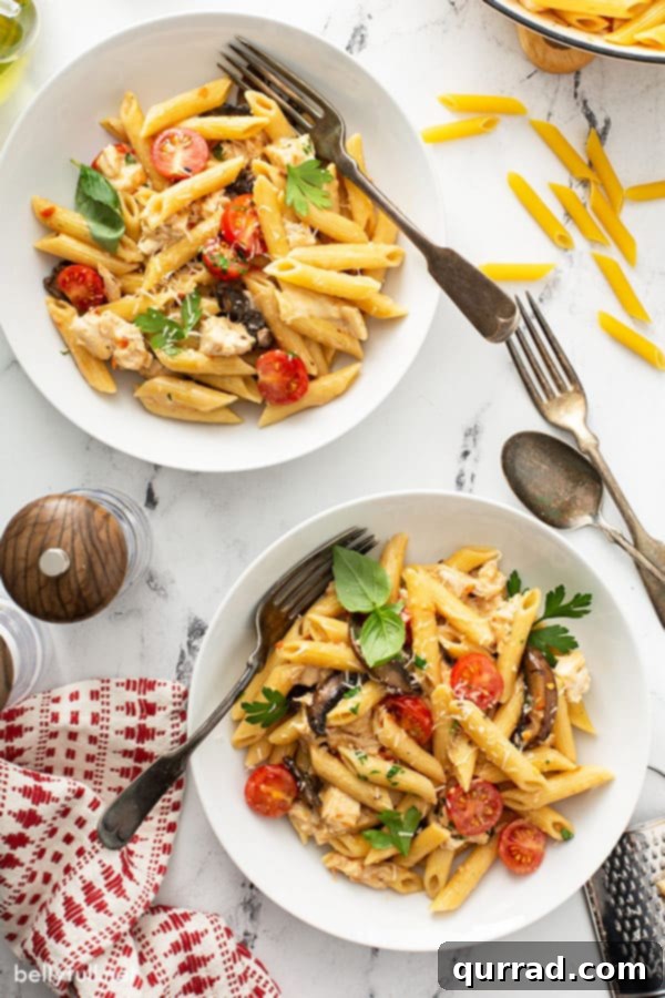 2 bowls filled with cooked penne pasta and chicken coated in sun dried tomato pesto sauce, ready to be served