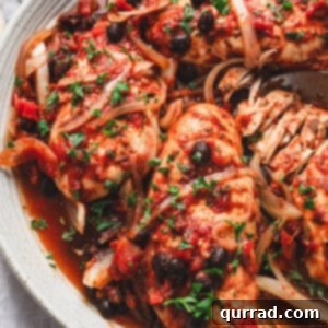 Tender Slow Cooker Balsamic Tomato Chicken 5 Close-up of slow cooker tomato balsamic chicken served on a platter with onions, black beans, and fresh parsley.