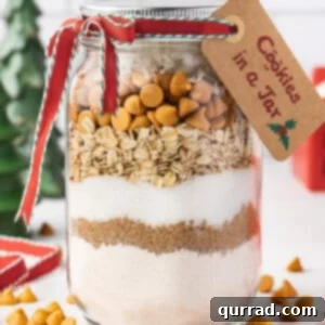 Layers of Cookie Joy 5 cookie mix layered in a glass jar with holiday tag and ribbon