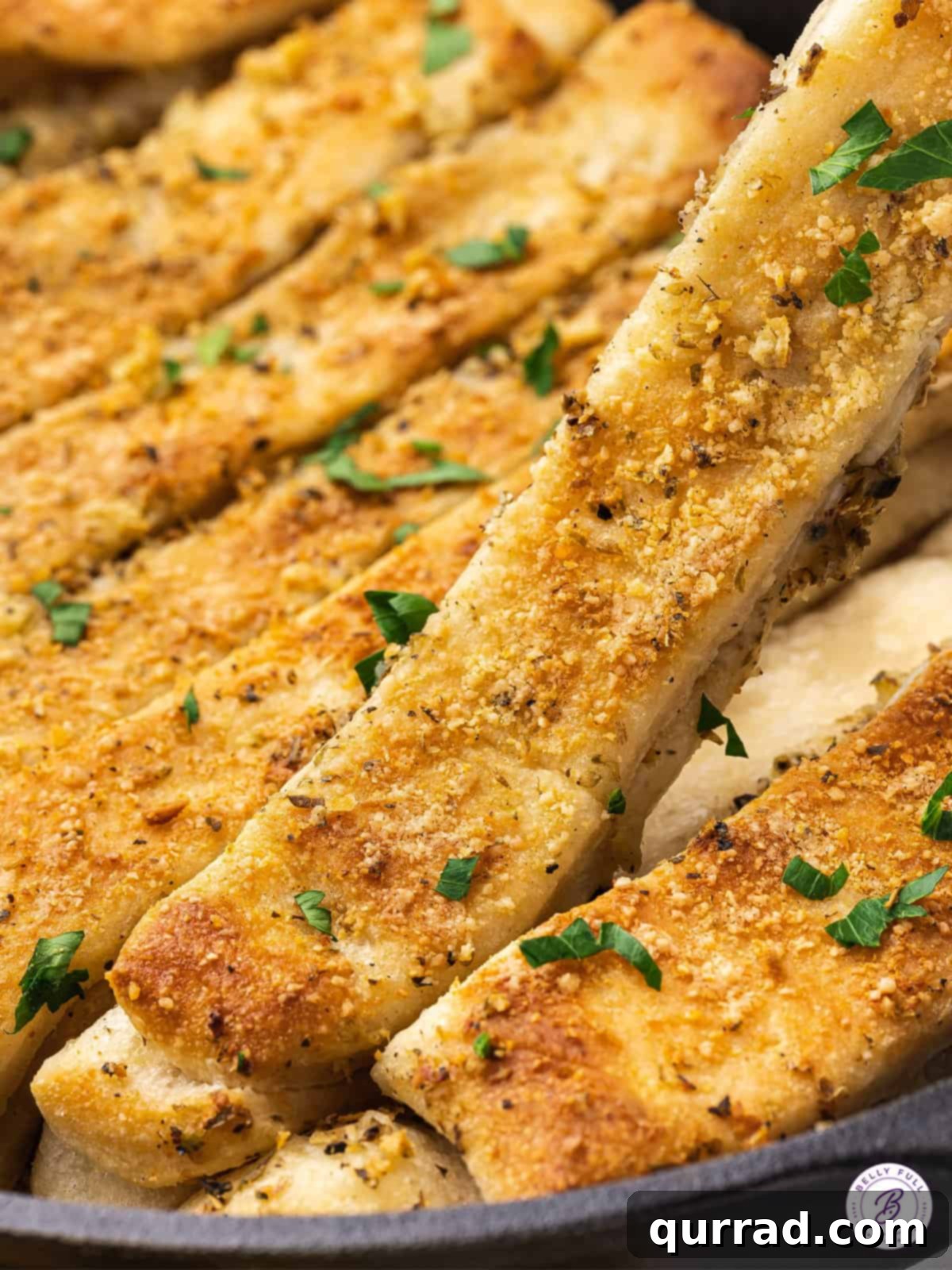 Effortless Skillet Breadsticks 2 Close-up of golden baked cheesy breadsticks, generously sprinkled with Parmesan, showcasing a crispy exterior.