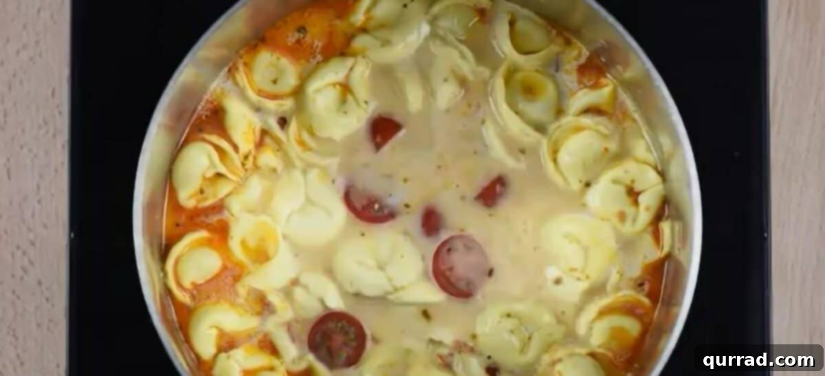 Adding cherry tomatoes to the pot of tortellini. 