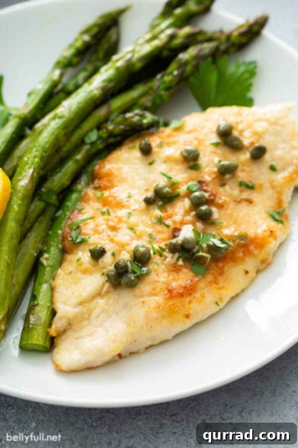Easy Chicken Piccata with Roasted Asparagus Close-up of golden-brown chicken piccata served on a plate with tender roasted asparagus and a garnish of fresh lemon and parsley.