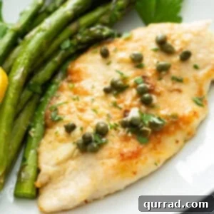 Close-up of golden-brown chicken piccata served on a plate with tender roasted asparagus.