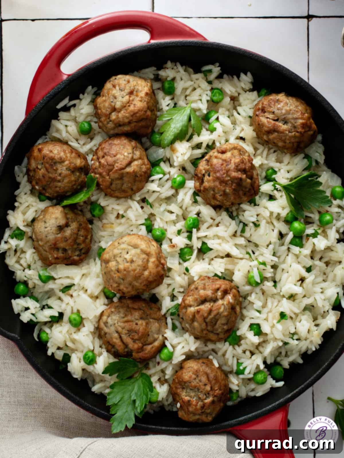 Overhead view of a cast iron skillet filled with a delectable Meatball Rice Skillet, featuring perfectly cooked rice, savory meatballs, and vibrant green baby peas, ready to be served.