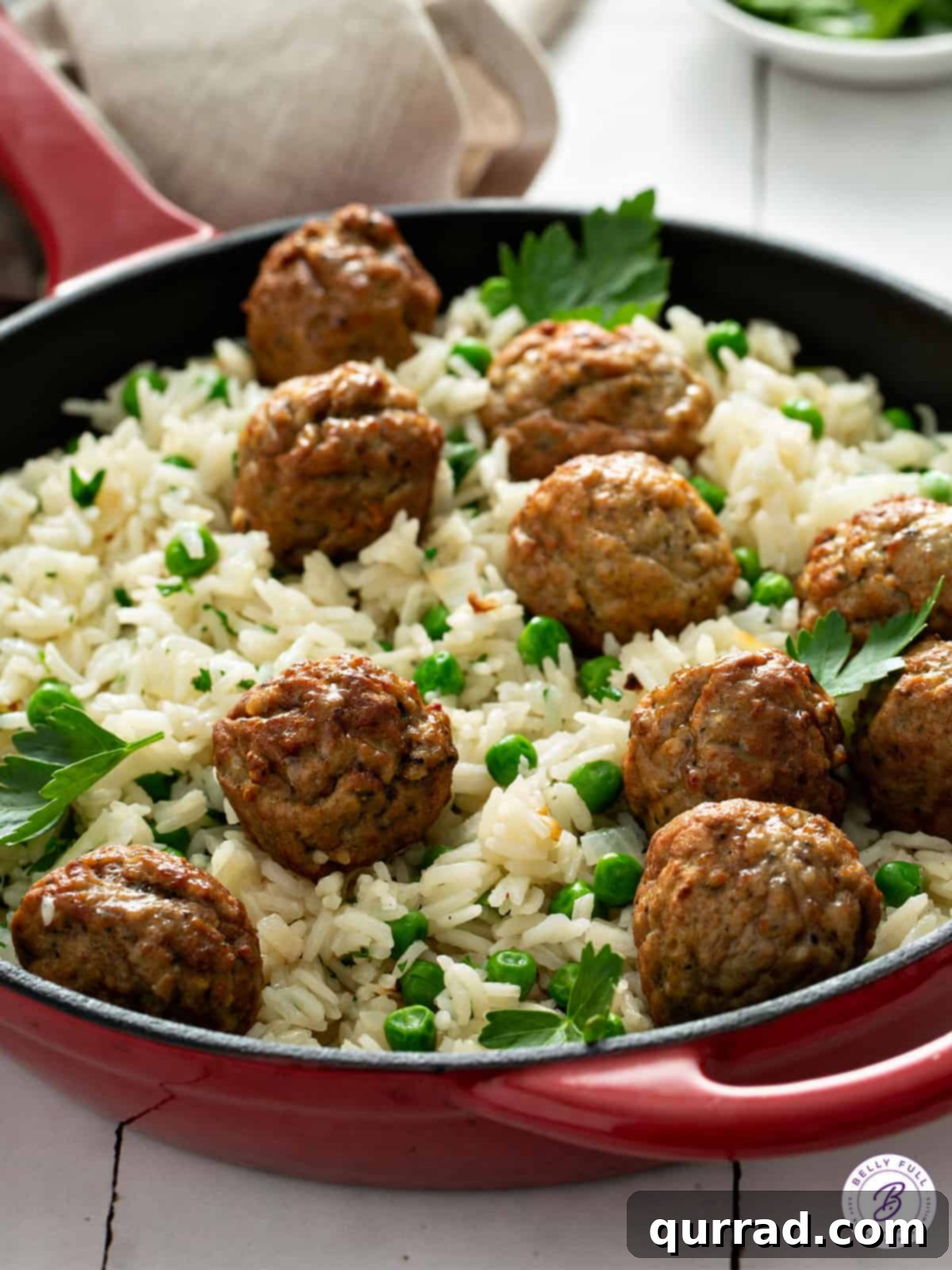 A serving of Meatball Rice Skillet in a bowl, garnished with fresh parsley, highlighting the fluffy rice, tender meatballs, and bright green peas, ready for enjoyment.