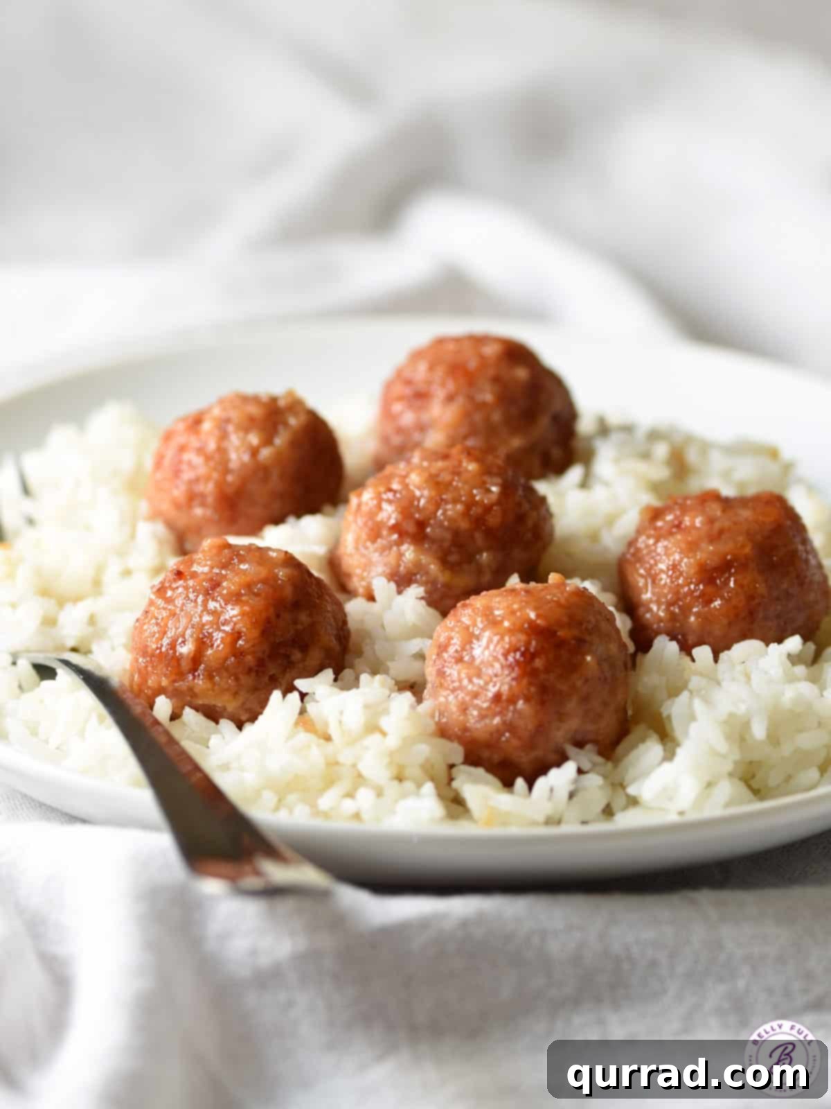 Savory Ham Bites 4 Individual ham meatballs glistening with glaze, served simply over cooked white rice.