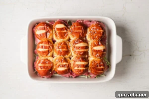 unbaked assembled pretzel bun sliders in casserole dish