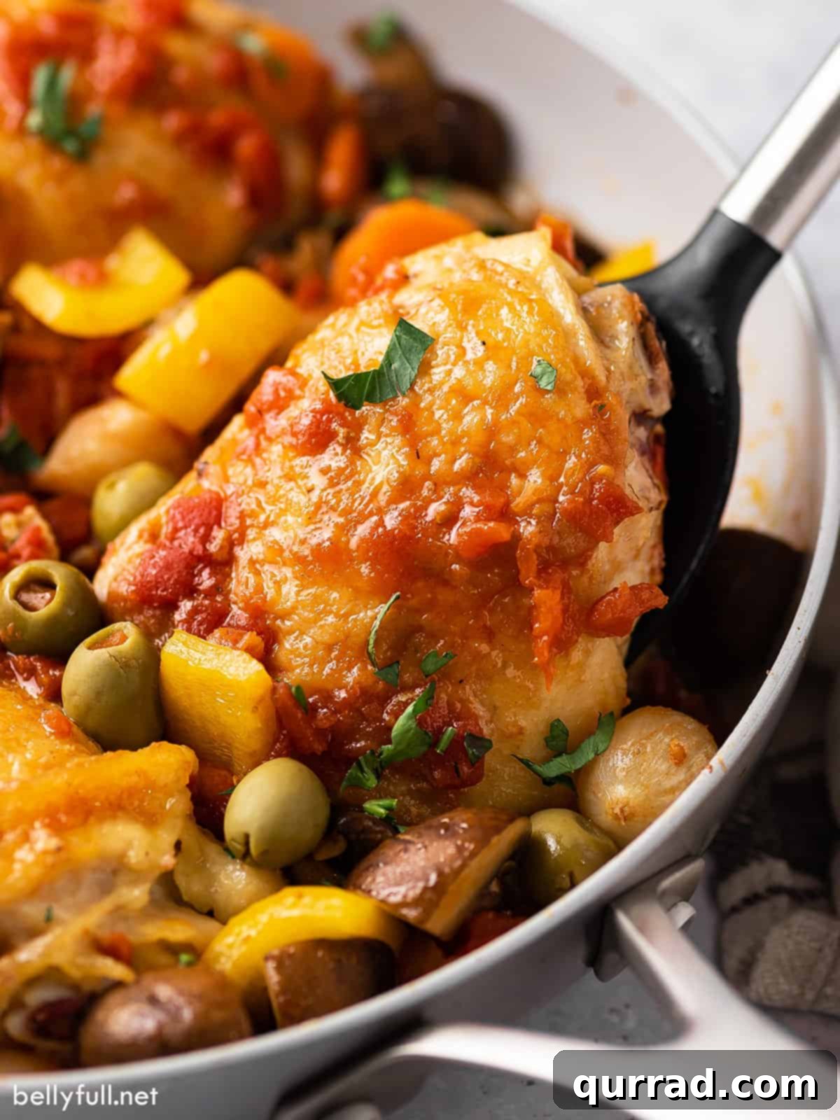 Rustic Italian Chicken Braise 3 Tender tomato-braised chicken thigh being lifted from a skillet, showing its succulent texture.