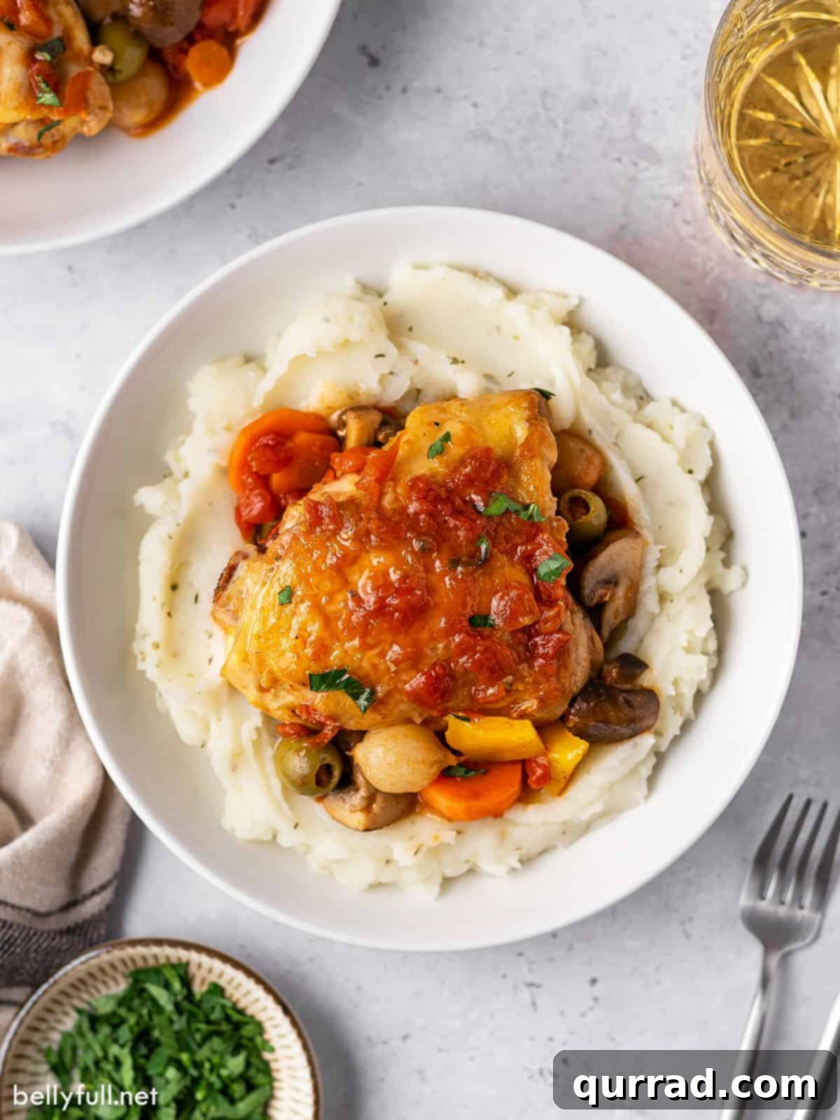 Rustic Italian Chicken Braise 4 Overhead view of Chicken Cacciatore served over a bed of creamy mashed potatoes in a shallow bowl.